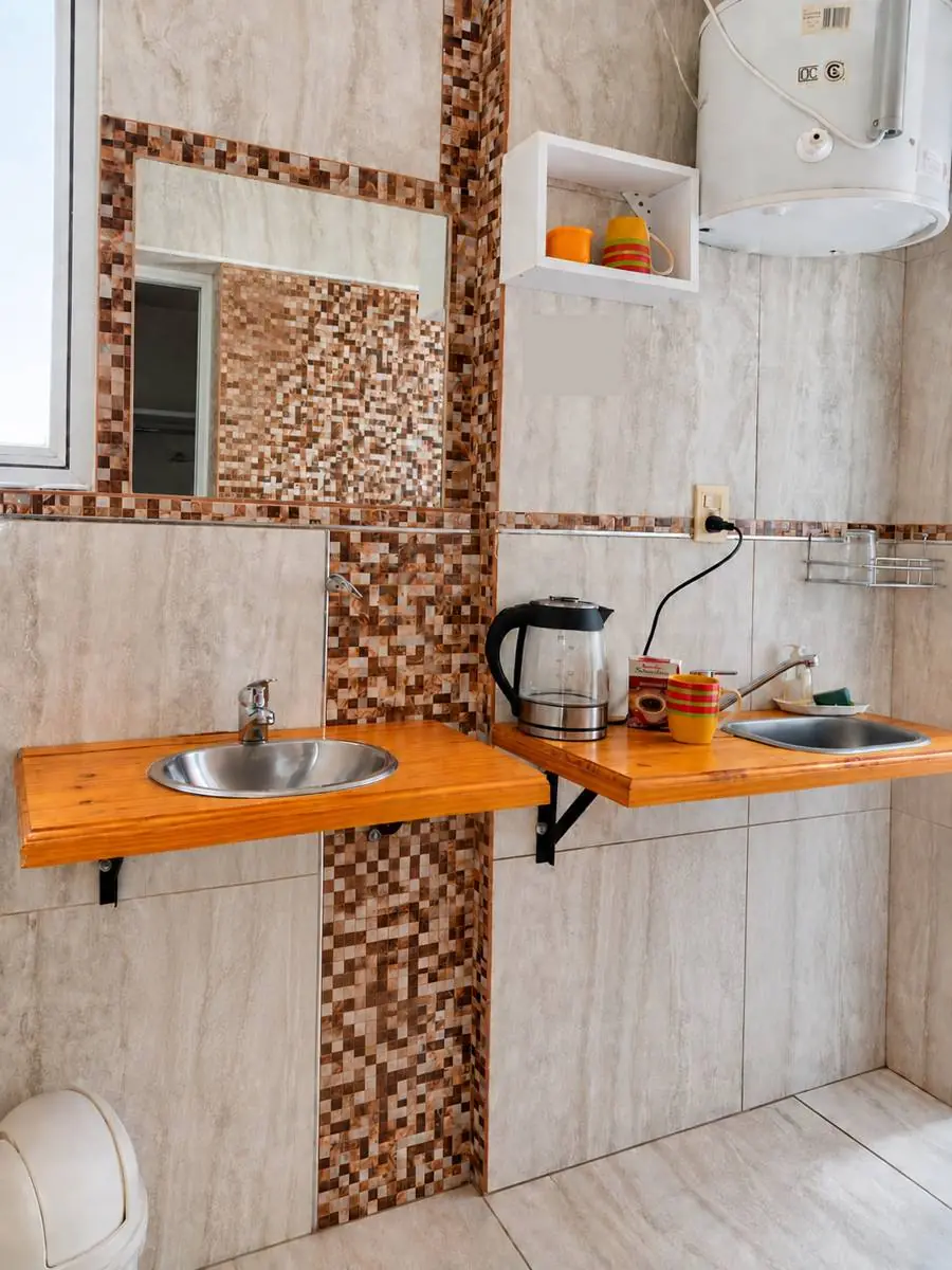 Bacha, pava eléctrica y tazas sobre mesada de madera