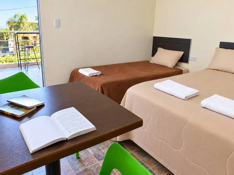 Habitación con camas, mesa y salida al balcón
