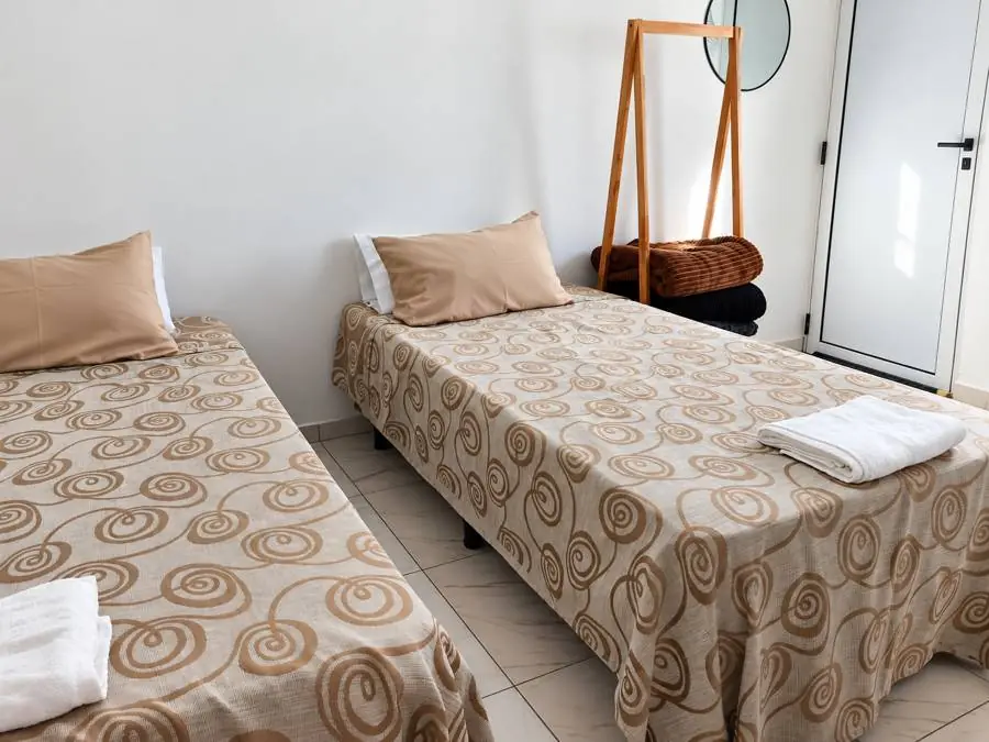 Camas individuales con toallas y perchero de madera