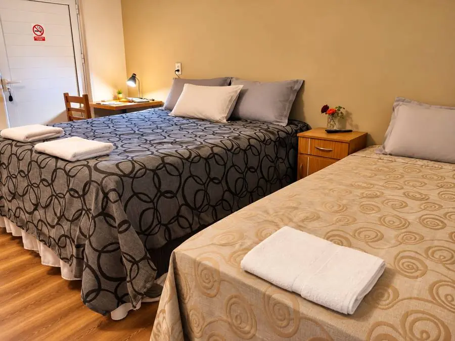 Habitación con cama grande, otra cama, escritorio y flores